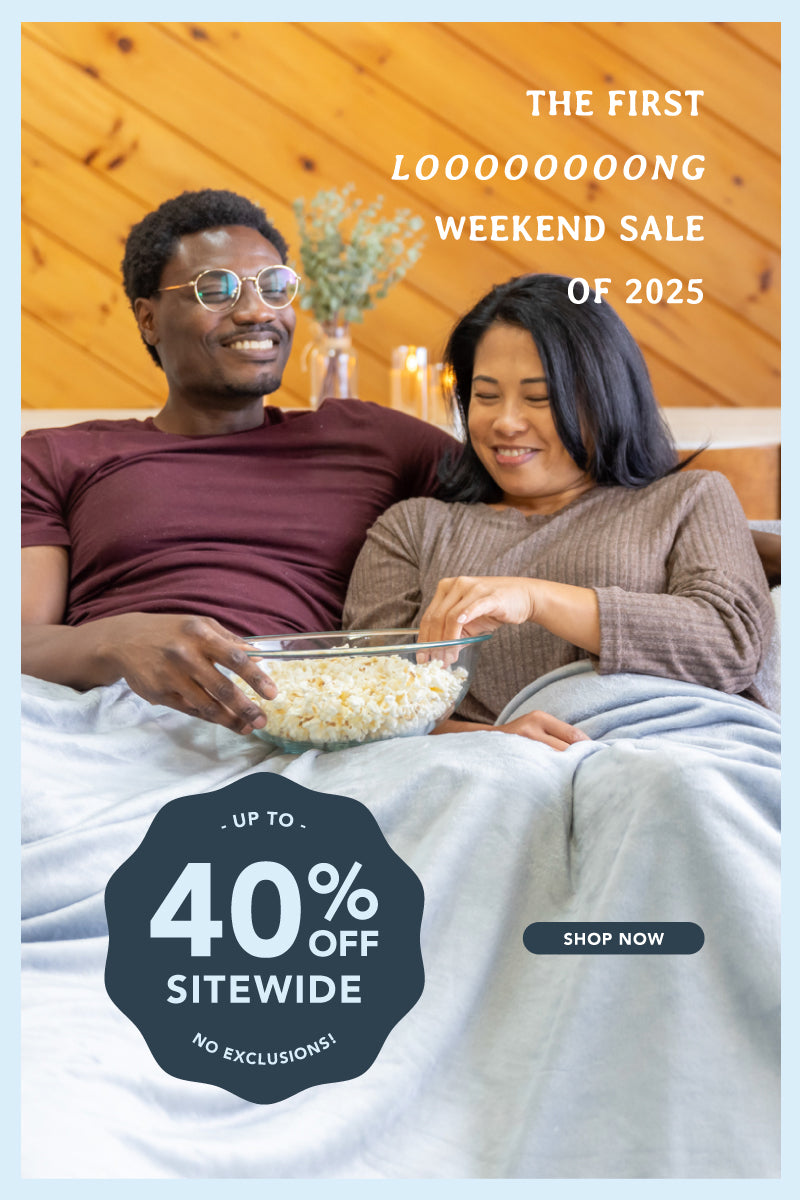 The first looooooong weekend sale of 2025, up to 40% off sitewide, no exclusions with 2 people sitting on a sofa eating popcorn wrapped in our VelvetLoft Family Blanket.