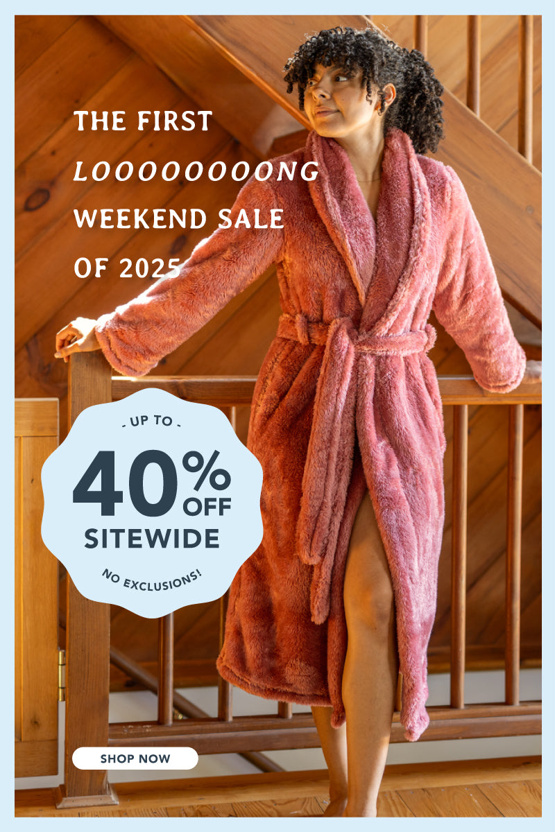 The first looooooong weekend sale of 2025, up to 40% off sitewide, no exclusions with a woman standing by a railing in a home wearing our pink Extra-Fluffy Robe.