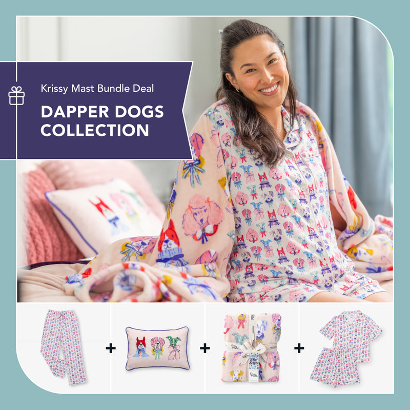 Smiling woman sitting on a bed wearing pastel Krissy Mast Dapper Dogs pajamas and wrapped in a matching printed blanket. Below her are product images showing Dapper Dogs pajama pants, an embroidered dog pillow, a printed throw blanket tied with ribbon, and a short-sleeve pajama set. Graphic text reads: ‘Krissy Mast Bundle Deal – Dapper Dogs Collection."