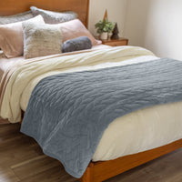 Bed with a blue quilt and pillows in a bedroom setting