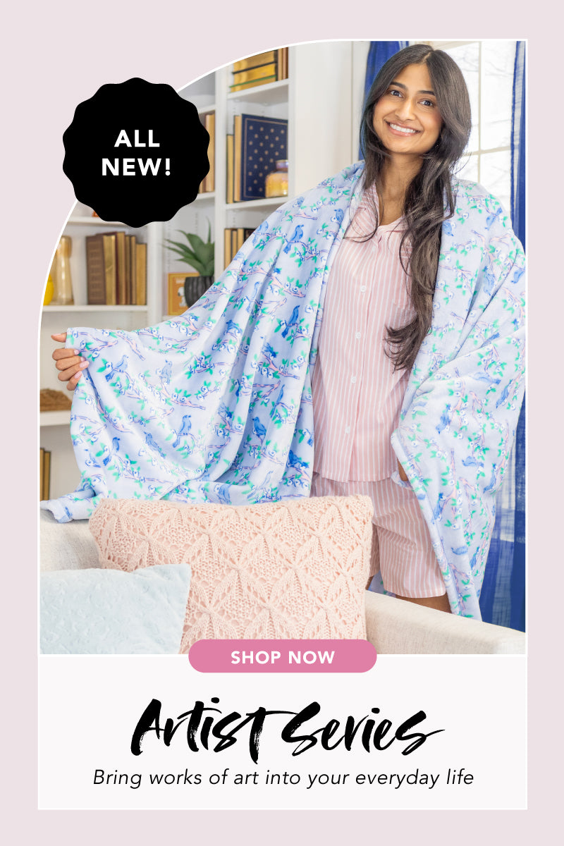 ALL NEW: Artist Series Collection. Bringing works of art into your everyday life. Shop now. Image of a woman on the couch with a throw featuring a blue and white hydrangea floral design.