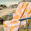 Vicky Yorke Summer Nostalgia beach towel draped over a beach chair by the sea.