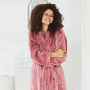 Woman wearing Extra-Fluffy™ Robe in Sunset Rose in a white bathroom.