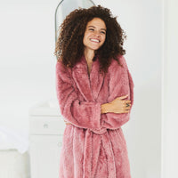 Woman wearing Extra-Fluffy™ Robe in Sunset Rose in a white bathroom.